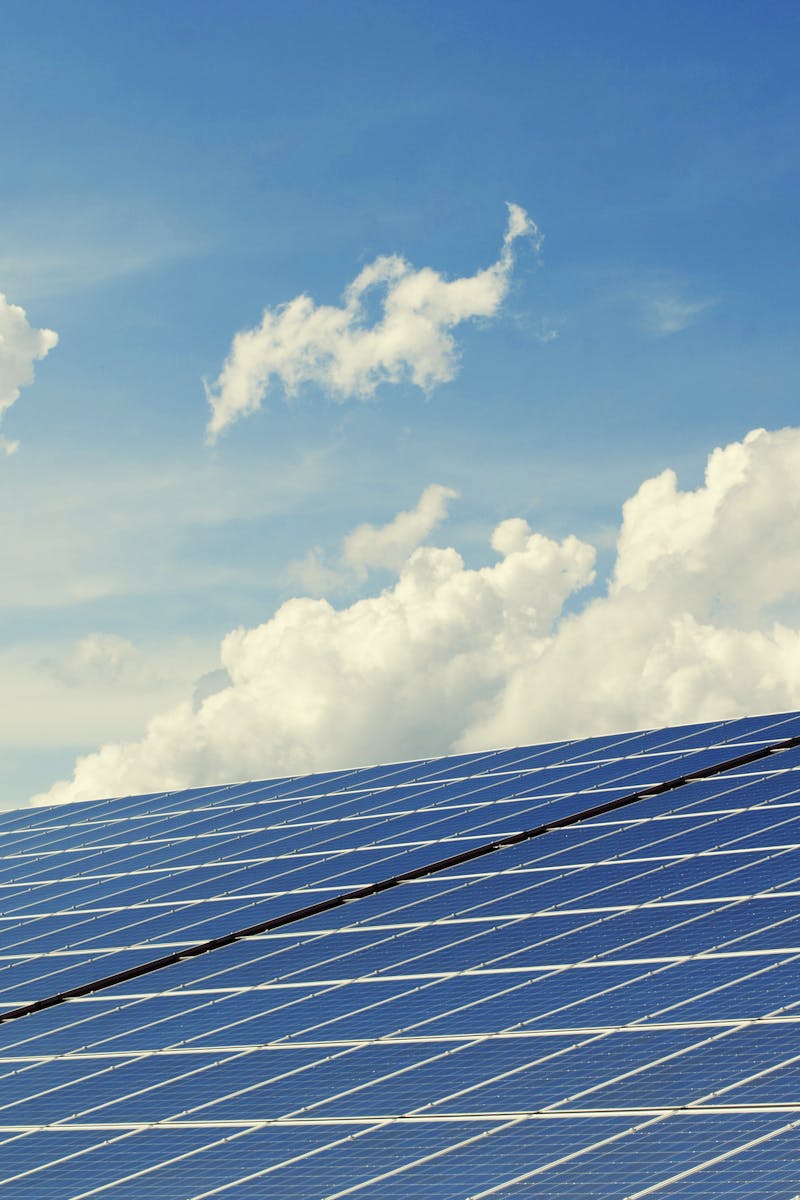 Sleek modern solar panels under a vibrant blue sky with clouds, symbolizing clean energy.